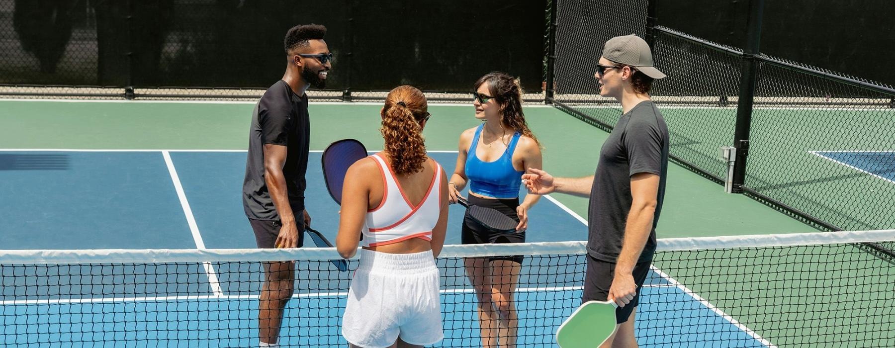 A group of people standing on a pickleball court.