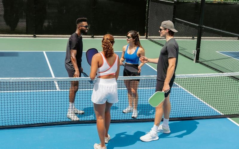A group of people standing on a pickleball court.
